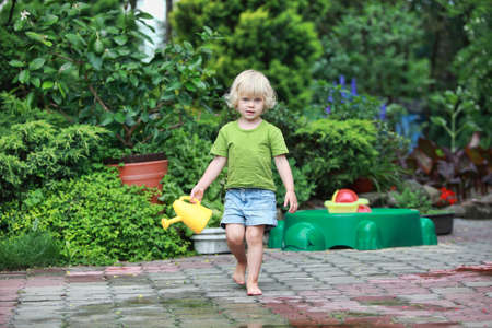 little barefoot girl with watering can - portraitの写真素材