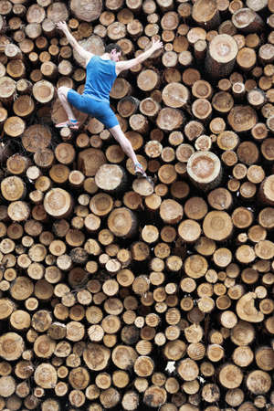 Fit climber going down the large pile of cut wooden logsの写真素材