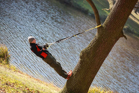suspension workout on tree - man at the outdoor training at the riverの写真素材