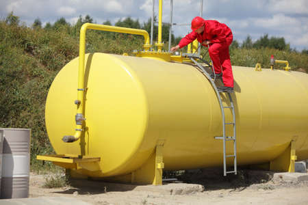 technician in red uniform working on large fuel tankの写真素材