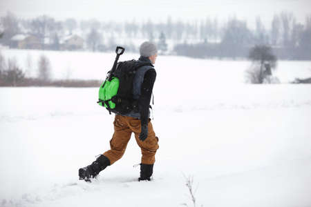 hiker - man with backpack walking  on snowy fieldの写真素材