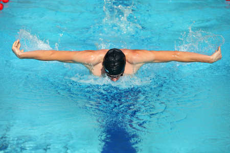  dynamic and fit swimmer in cap breathing performing the butterfly stroke 