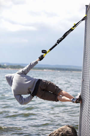 hooded man outdoor,suspension training at the sea