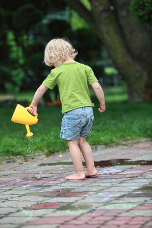White little barefoot girl playing with water canの写真素材