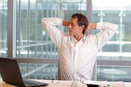 white collar worker male stretching arms, relaxing neck - short break for exercise on chair in officeの写真素材