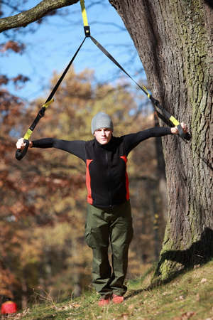 outdoor suspension training in forest - caucasian  man at tree