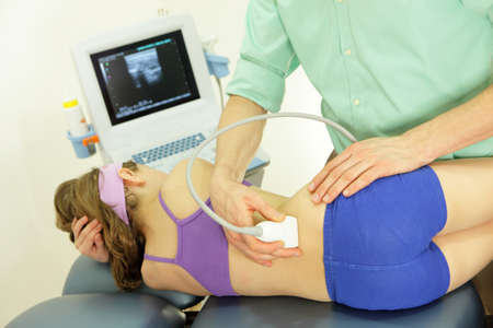 girl's lower back diagnosis carried out with the use of an ultrasoundの写真素材