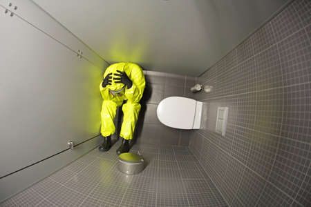 nervous breakdown - man in protective coverall hiding in the toiletの写真素材