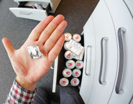 hand holding blister with pills - office environment - first person view