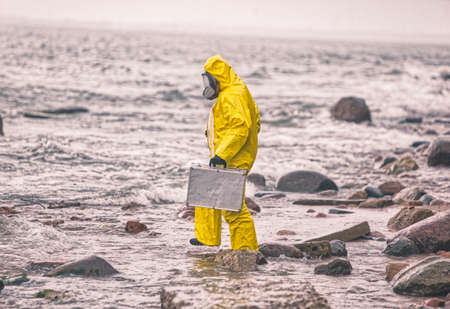 scientist in protective suit with silver case walking on rocky beach