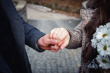 man holds the hand of a girl with golden ringsの写真素材