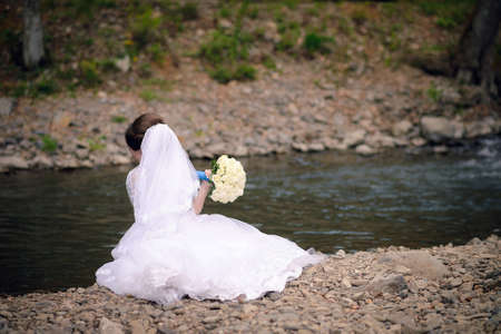 Bride sitting by the river in the parkの写真素材