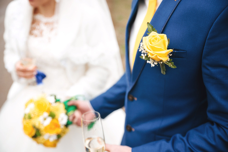 couple in love holding a yellow bouquet and glass of champagneの写真素材