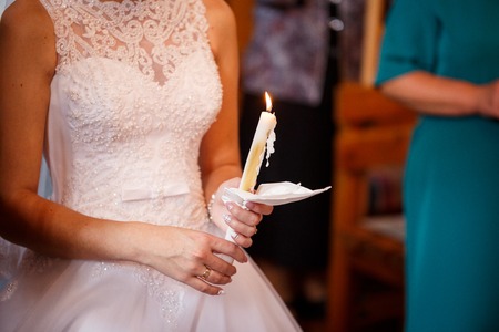 loving couple holding candles at the wedding ceremony in churchの写真素材