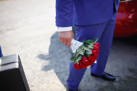 man in blue suit holding a magnificent bouquet of rosesの写真素材