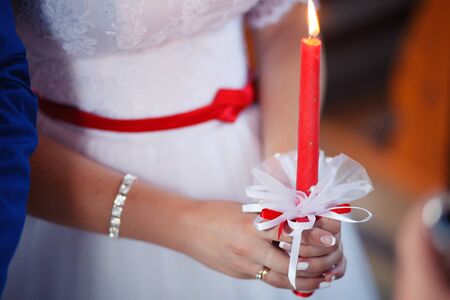Bride in beautiful dress with lighted candles on wedding ceremony in churchの写真素材