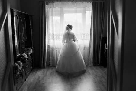 bride standing at the window and waiting for a loved oneの写真素材