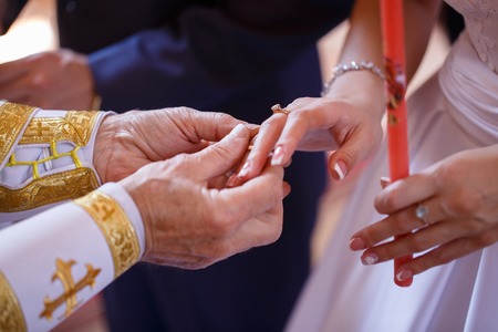 priest wears gold rings for bridesの写真素材