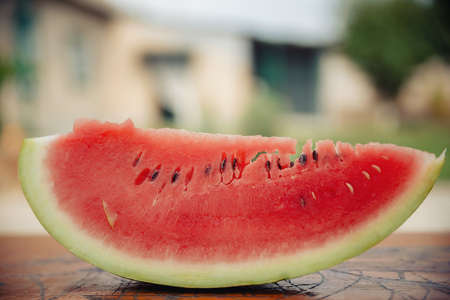 A man with a stylish hairstyle, a long beard and a tattoo with great pleasure eats watermelonの写真素材
