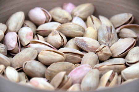 Salted pistachios in a wooden plate close up.