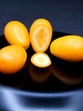 Yellow ripe kumquat on a black background. Exotic fruit.の写真素材