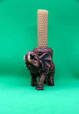 Figurine of an Indian elephant on a green background close-up. Candlestick in the shape of an Indian elephant.の写真素材