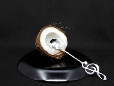 Half a coconut with pulp and a dessert spoon on a gray background. Half a coconut close up.の写真素材