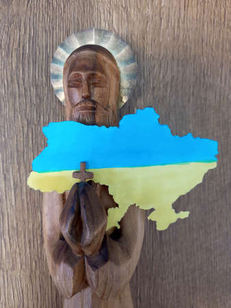 Wooden figurine of a saint with a map of Ukraine in the color of the yellow-blue Ukrainian flag.の写真素材