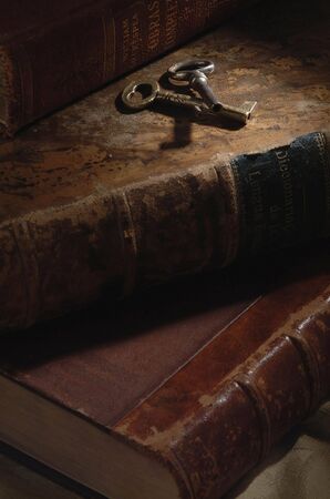 Old keys over aged booksの写真素材
