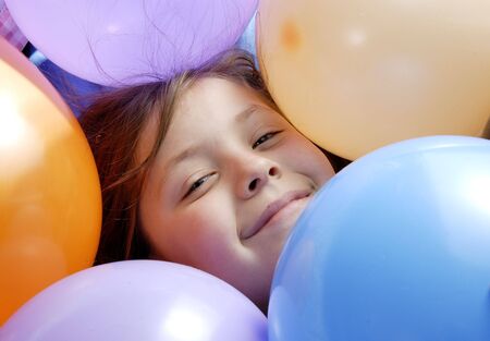 a small girl surrounded with balloonsの写真素材