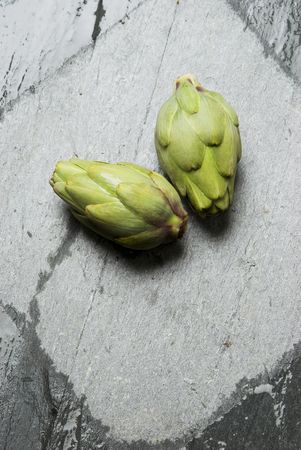 Two artichokes flowers without stem over a limestone stone with a square drawn on the stone, scientific name cynara scolymus.の写真素材