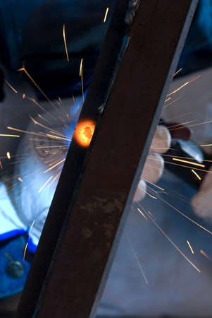 welder with protective mask soldering a piece of iron