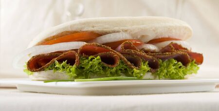 pastrami,onion,tomato and lettuce sandwich over a table