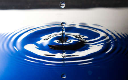 Water droplet splashing into bowl with water