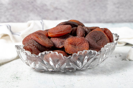 Dried apricots on stone background. Dark dried apricots in a glass bowl. diet food. close up