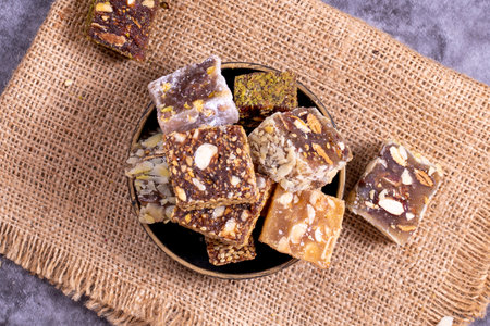 Mixed Turkish delight varieties on a dark background. Pistachio, hazelnut and fruit flavored Turkish...