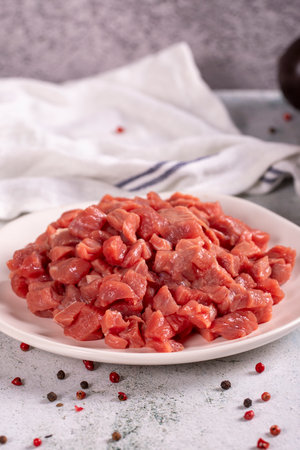 Cubed meat. Red meat in a chopped plate on a stone floor. Butcher products. close upの写真素材