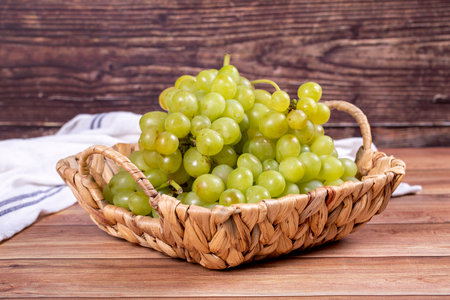 Fresh green grapes. Ripe grapes in basket on wood background. Bulk grapes. close upの写真素材
