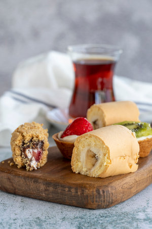 Delicious snacks. Roll cake, chocolate chip cake and fruit tart on a stone background. close up