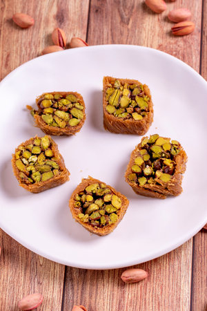 Pistachio kadayif dessert. Kadayif baklava with pistachio filling on a wooden floor. Turkish cuisine desserts. close-up. local name pistachio kadayifの写真素材