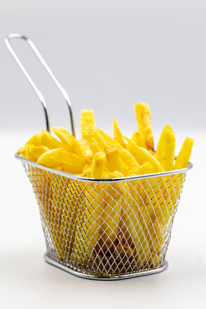 Fried potatoes. French fries on white background. French fries served in a roasting wire. close up