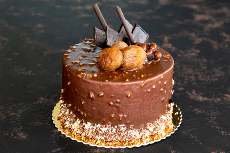Chestnut and chocolate birthday cake on dark background