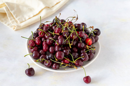 Ripe fresh cherries on a white ceramic plate