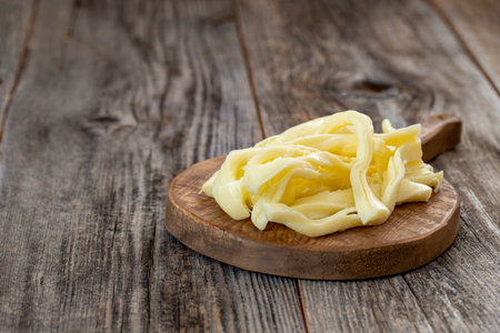 Chechil cheese or string cheese on wood floor. Cheese on serving board
