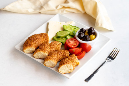 Breakfast plate on a white background. Bagels, feta cheese, olives, tomatoes and cucumbers.