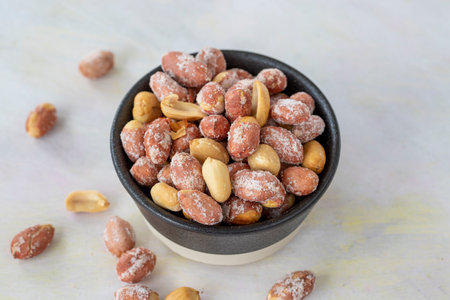 salted peanuts in bowl on white wooden background