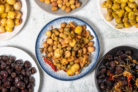 Olive varieties. Assortment of black and green olives on plate on gray background. Top viewの写真素材