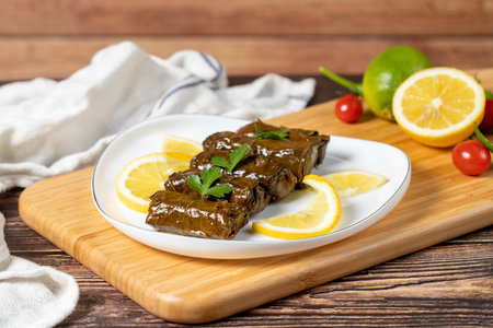 Olive oil leaf wrap. Turkish cuisine delicacies. Wrapping grape leaves on wood background. Local...