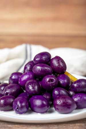 Kalamata olive with blueberries flavor. Purple olives on wood background. close upの写真素材