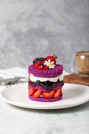 Layered fruitcake. Cake with strawberries, raspberry sauce and cream on a stone background. Patisserie dessertsの写真素材
